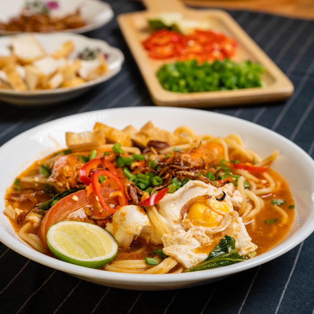 Mee Bandung entices with its vibrant blend of spicy, tangy, and savory flavors, as the rich tomato-based broth harmonizes perfectly with the springy noodles, creating a tantalizing Malaysian culinary masterpiece.